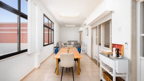 A modern dining area with a long table, chairs, and a white cabinet with baskets. - Algarve Townhouse in Loulé by MGM Stays (Loulé)