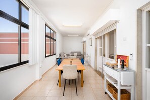 A modern dining area with a long table, chairs, and a white cabinet with baskets. - Algarve Townhouse in Loulé by MGM Stays (Loulé)