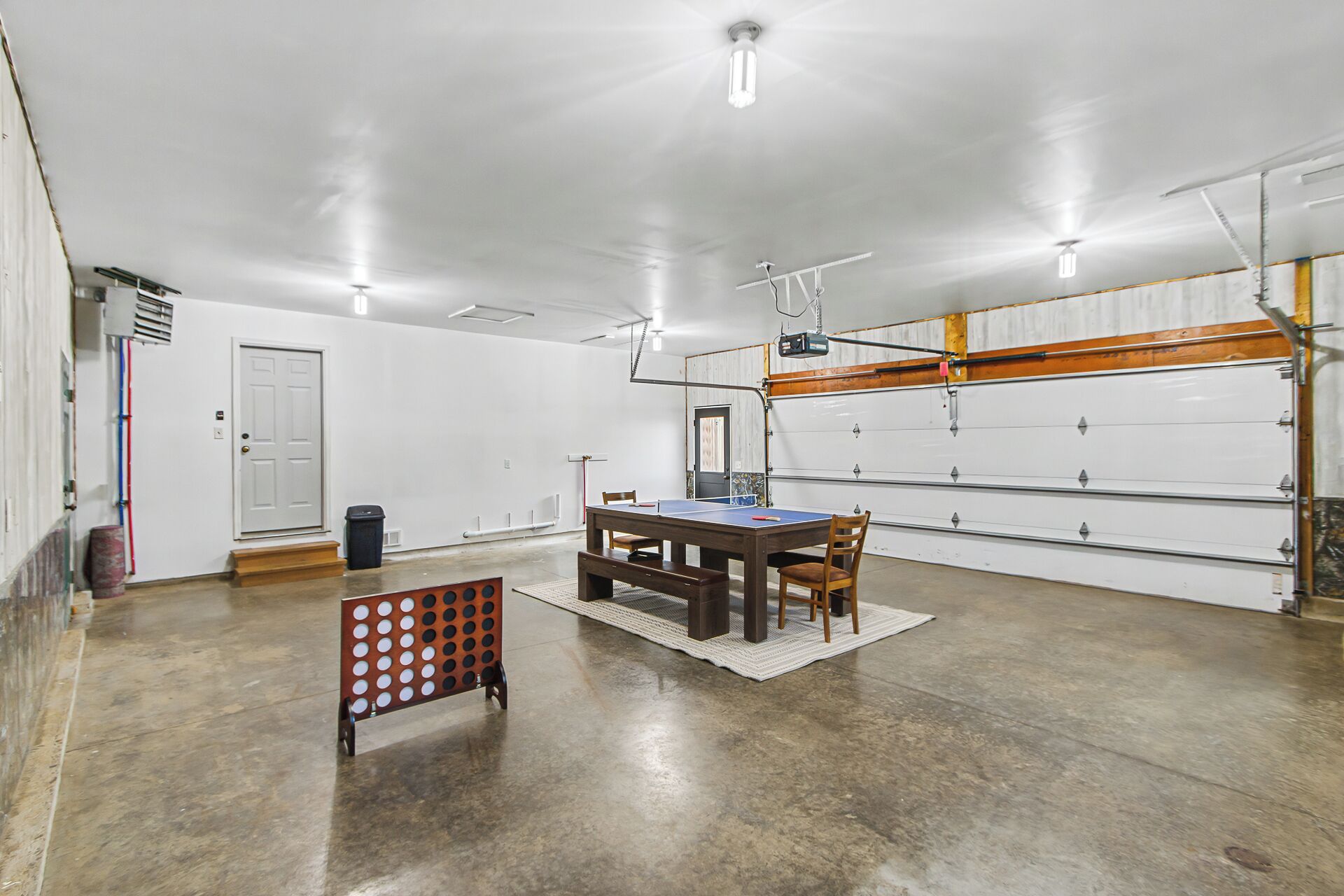 Un amplio espacio interior con mesa de ping pong, sillas y un banco de madera.