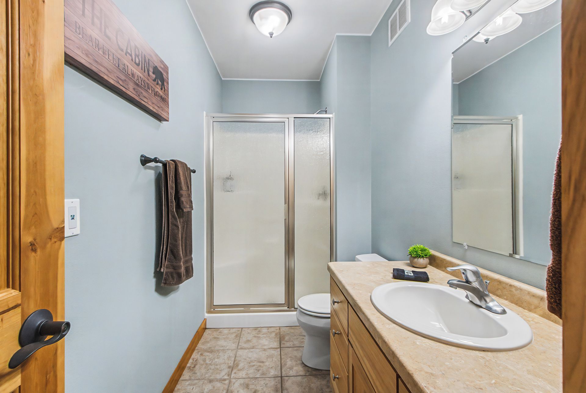 Un baño con ducha, inodoro, lavabo y un perchero para toallas.