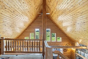 A wooden interior with a sloped ceiling, a wooden staircase, and a view of a green landscape through windows. - KwikStay: Amish Country Lodge//Hottub & Sauna (Hill Point)