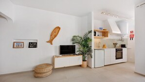 A modern kitchen with white cabinets, a built-in oven, and a dining area with a wooden table and chairs. - Lemon House – Cozy Home Near the Beach and City Center (Lagos)