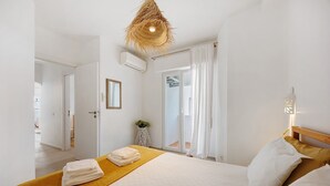 A hotel room with a bed, a yellow bedside table, a hanging light fixture, and a view of the outside. - Lemon House – Cozy Home Near the Beach and City Center (Lagos)