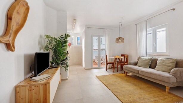 A living room with a television, a sofa, a dining table, and a large plant. - Lemon House – Cozy Home Near the Beach and City Center (Lagos)