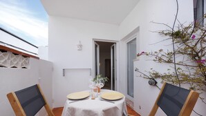 A small outdoor dining area with a table set for two, surrounded by chairs, a white tablecloth, and a potted plant. - Lemon House – Cozy Home Near the Beach and City Center (Lagos)