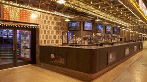 Eine Bar mit einer Theke, mehreren Bildschirmen und einer Wand mit Muster.