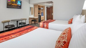 Ein Hotelzimmer mit zwei Betten, einem Schreibtisch, einem Stuhl, einem Fernseher und einem Kleiderschrank.