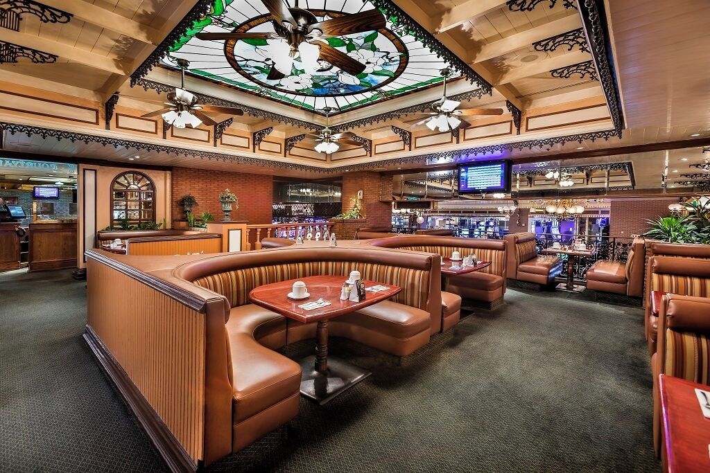 A restaurant with booth seating, a bar area, and a stained glass ceiling.