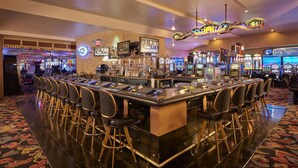 Zona de bar con máquinas de juego, mostrador y varios taburetes.