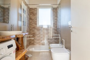 Une salle de bain moderne avec un grand miroir, un meuble-lavabo en bois, un espace douche et des toilettes.