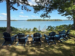 Un espace aménagé au bord du lac, avec des chaises Adirondack et un quai.