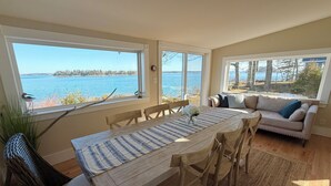 Zona pranzo con tavolo, sedie e vista sull'acqua.