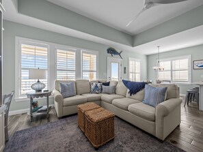 Ein Wohnzimmer mit Ecksofa, Couchtisch, Teppich und Deckenventilator.