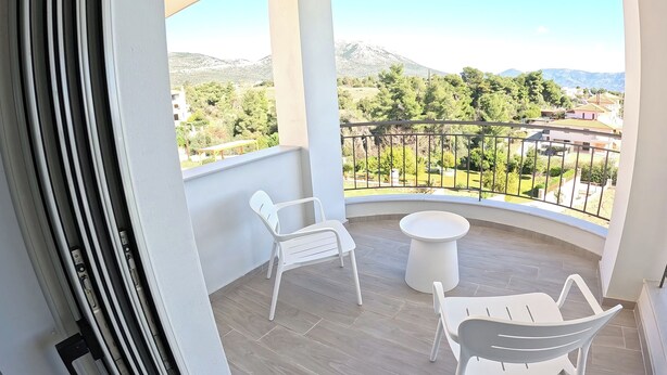 A balcony with a view of a mountainous landscape, two white chairs, and a small round table. - Villa Merimonti The horizon between sea and mountains (Érétrie)