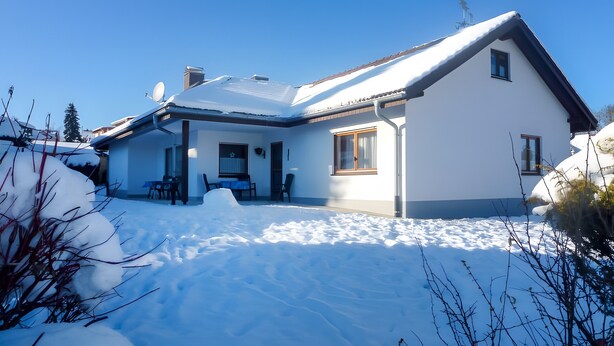 Une maison à deux étages, dont le toit est recouvert de neige et sur laquelle on peut voir une antenne parabolique.