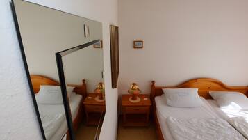 Une chambre d’hôtel avec deux lits, une tête de lit en bois, une table de chevet avec une lampe, un miroir et un petit tableau encadré accroché au mur.