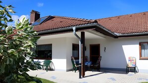 Une maison avec un toit en tuiles, un patio couvert et une antenne parabolique.