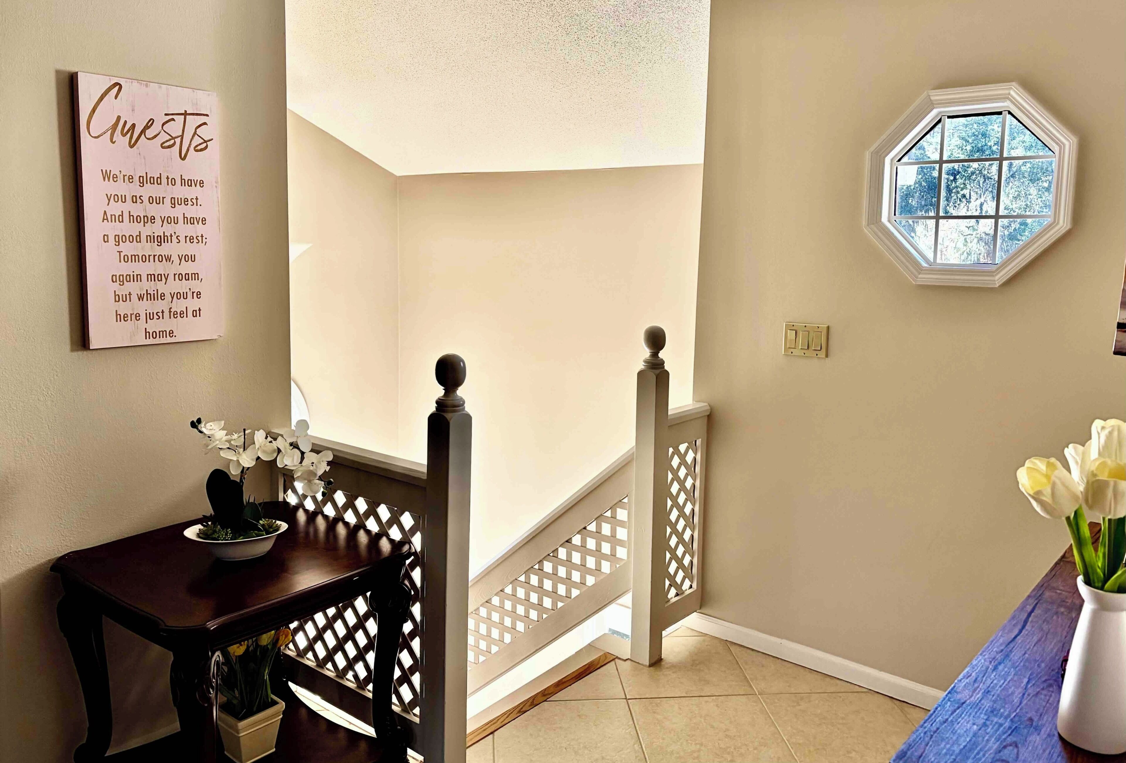 A staircase with a white railing, a wall-mounted sign, and a window with a view of trees.
