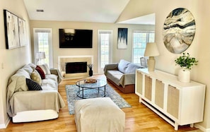 A living room with a fireplace, sofas, a coffee table, and a TV.