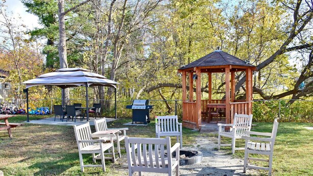A gazebo with a grill, outdoor seating, and a covered picnic area. - Unit 7 Beach Retreat | Walk to Shore | BBQ + Fire Pit (Wasaga Beach)