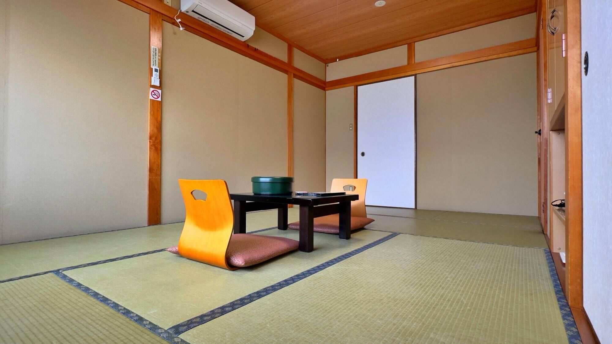A traditional Japanese room with tatami flooring, a low table with cushions, and sliding doors.