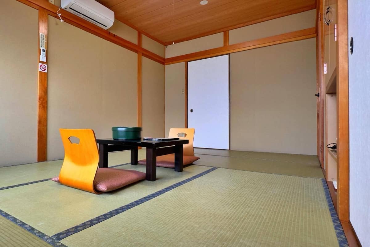 A traditional Japanese room with tatami flooring, a low table with cushions, and sliding doors.