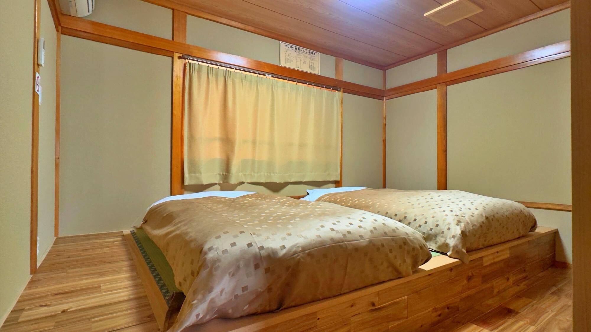 A room with a wooden bed, a window with a curtain, and a wooden ceiling.