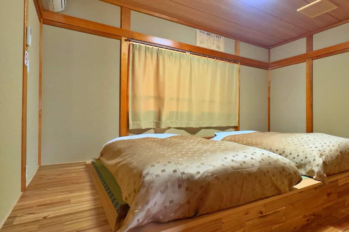 A room with a wooden bed, a window with a curtain, and a wooden ceiling.