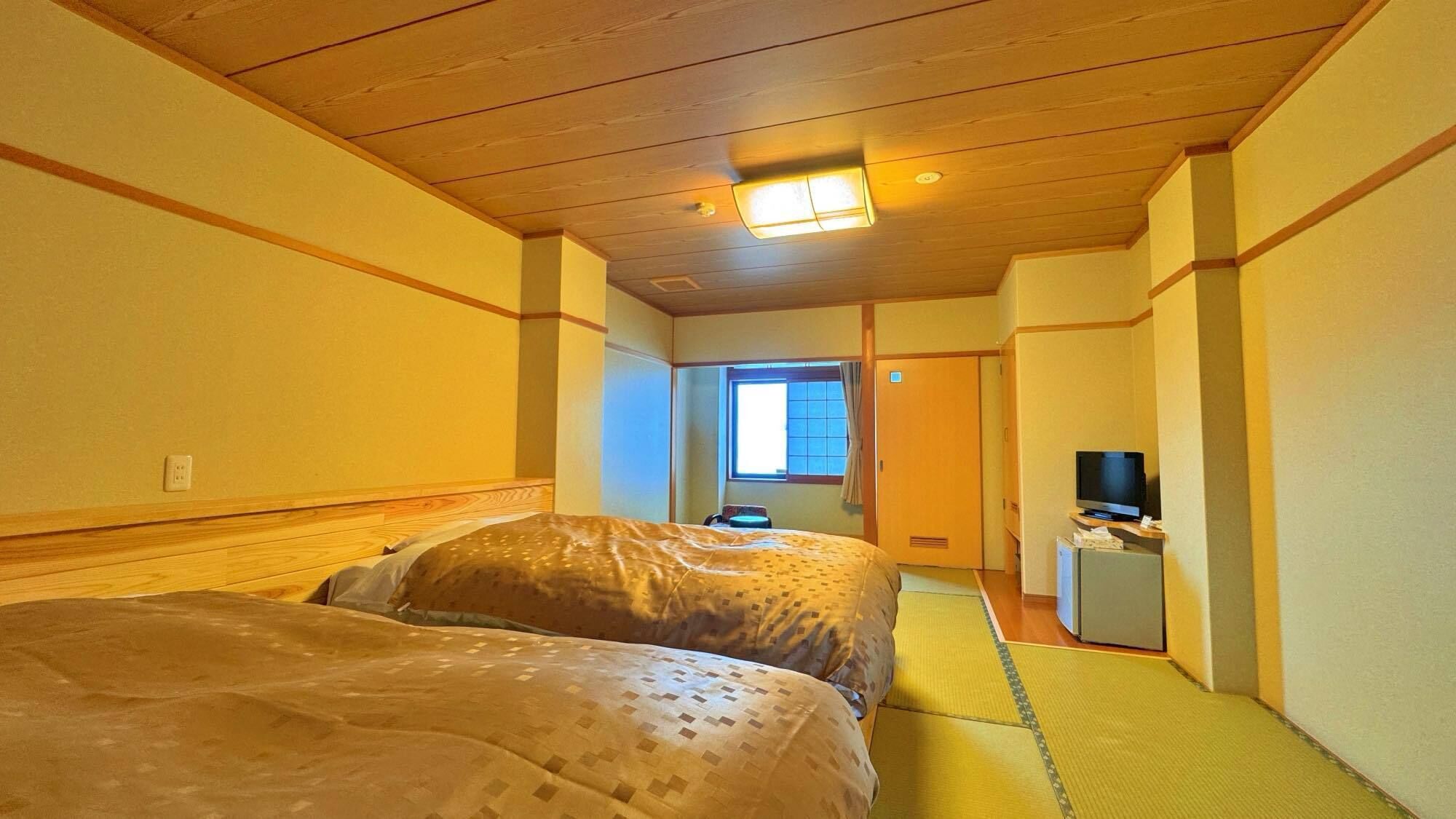 A hotel room with two beds, a television, and a small desk.