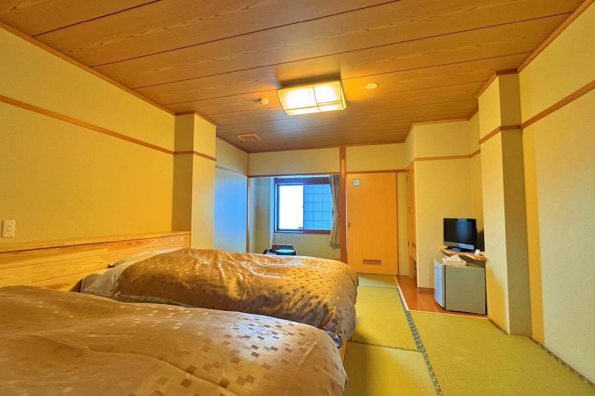 A hotel room with two beds, a television, and a small desk.