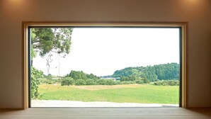 A room with a large window overlooking a green field and trees. - Yuushinan (Nanao)