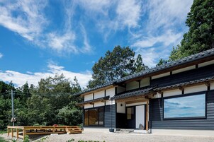 Un edificio tradicional japonés con un amplio puertas correderas y un banco de madera en el exterior.