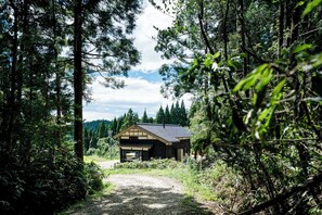 A cabin surrounded by dense forest, with a gravel path leading to it. - Yuushinan (Nanao)