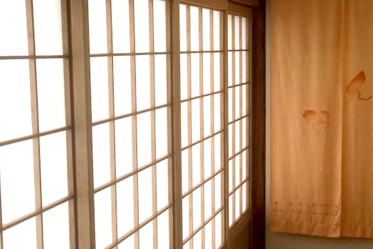 Une pièce dotée d’une porte coulissante de style japonais (shoji) et d’un rideau orné de motifs floraux.