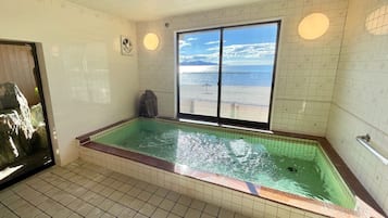 Una habitación con un ventanal grande, una bañera y un ventilador en la pared.