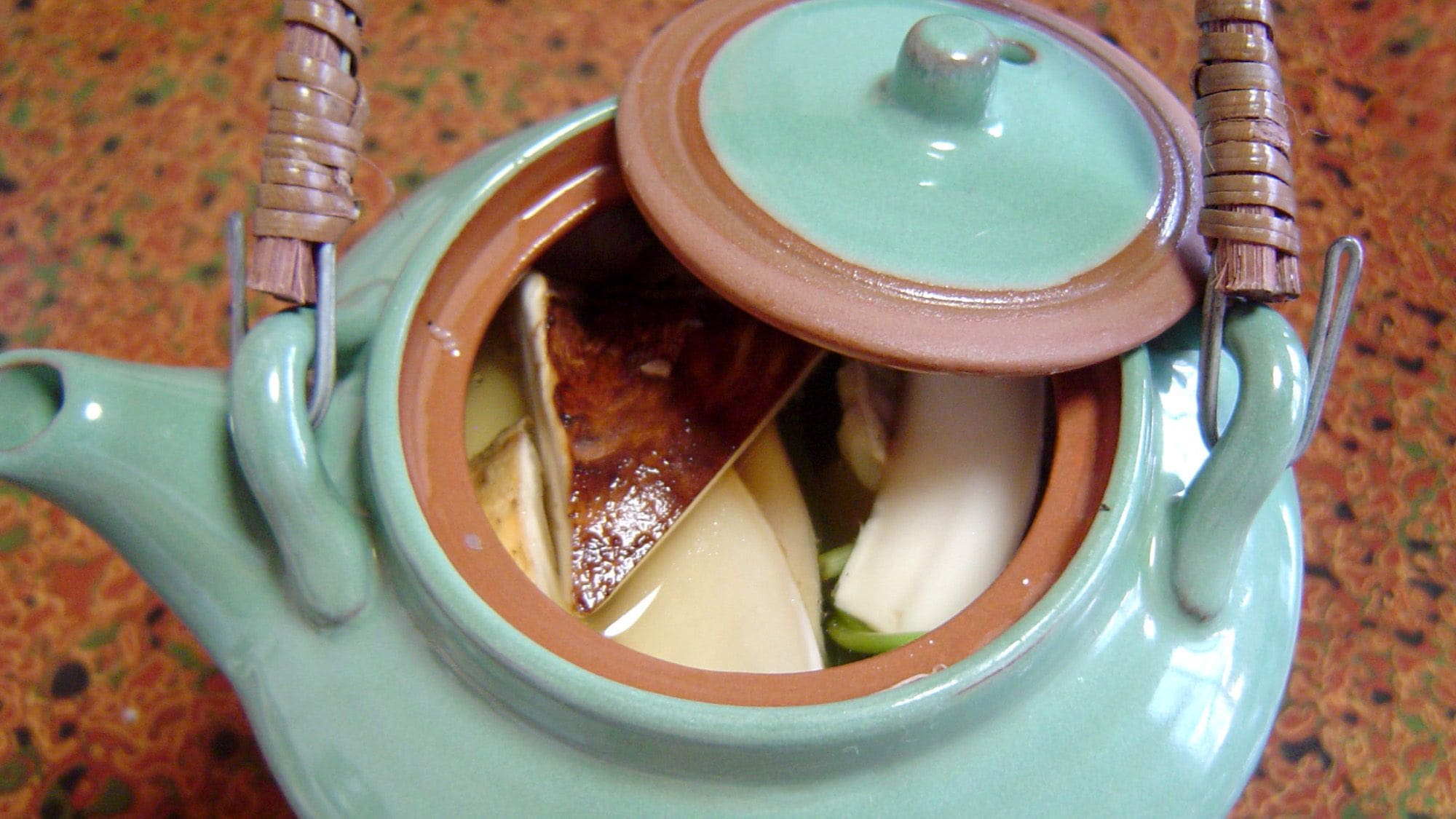 A ceramic teapot with a lid and handles.