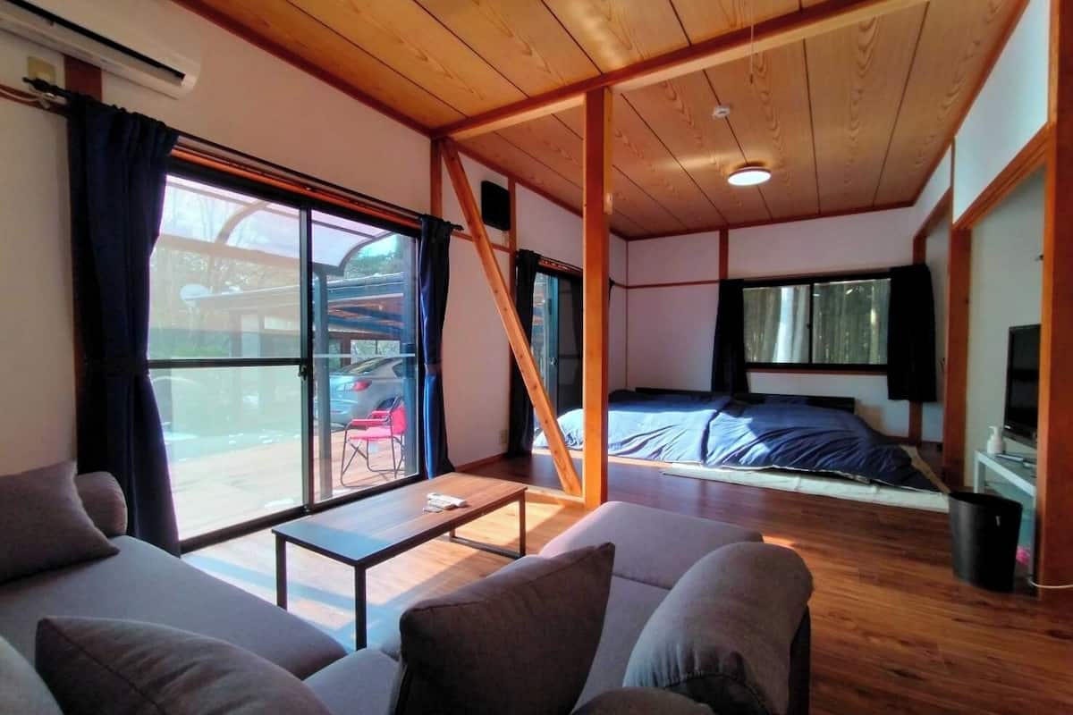 Habitación con sofá, cama, televisión y ventana con vista a coches estacionados.
