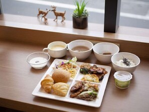 A breakfast tray with various foods and drinks on a wooden table near a window. - Super Hotel JR Nara Station Sanjo Street (Hikone)