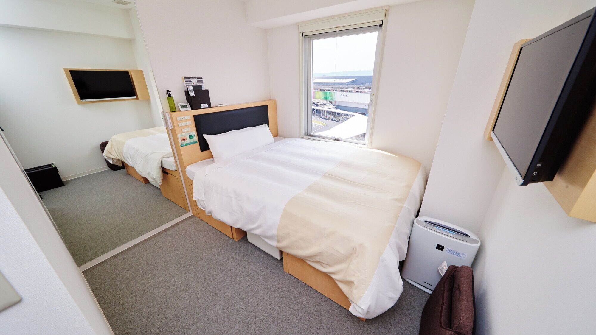 Ein Hotelzimmer mit zwei Betten, einem Fernseher, einem Fenster mit Blick und einer Heizung.