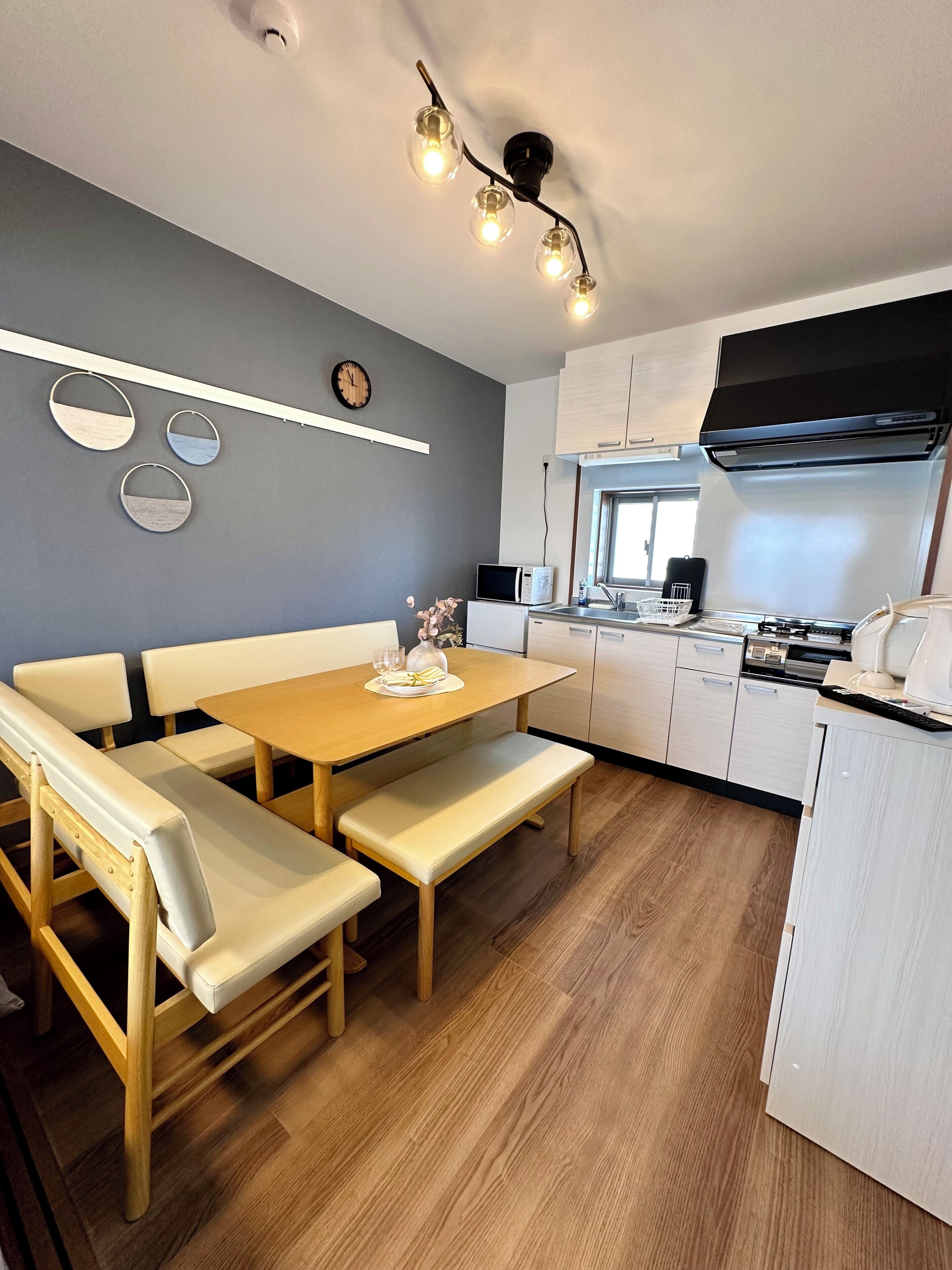 A modern kitchen with a wooden dining table, bench seating, a microwave, and a stove.