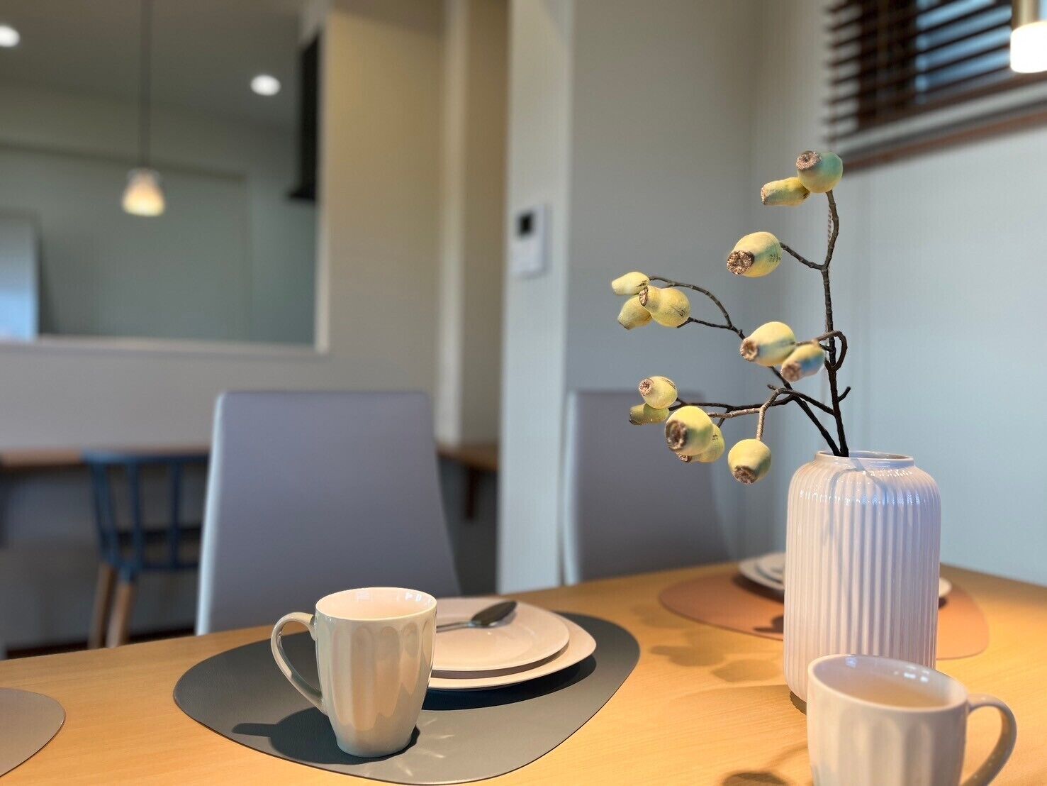 A dining table with a vase of flowers, a cup, and a plate.