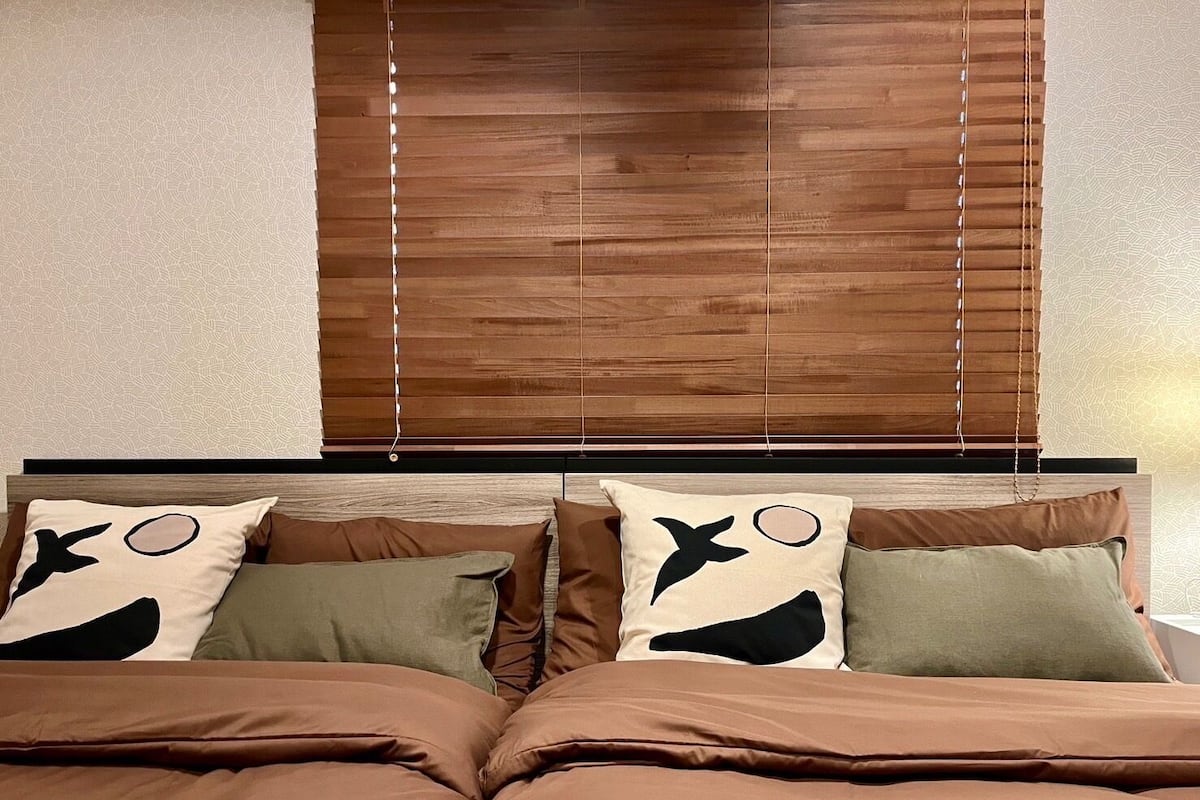 Un dormitorio con cama, dos almohadas con motivos de animales y persianas de madera.