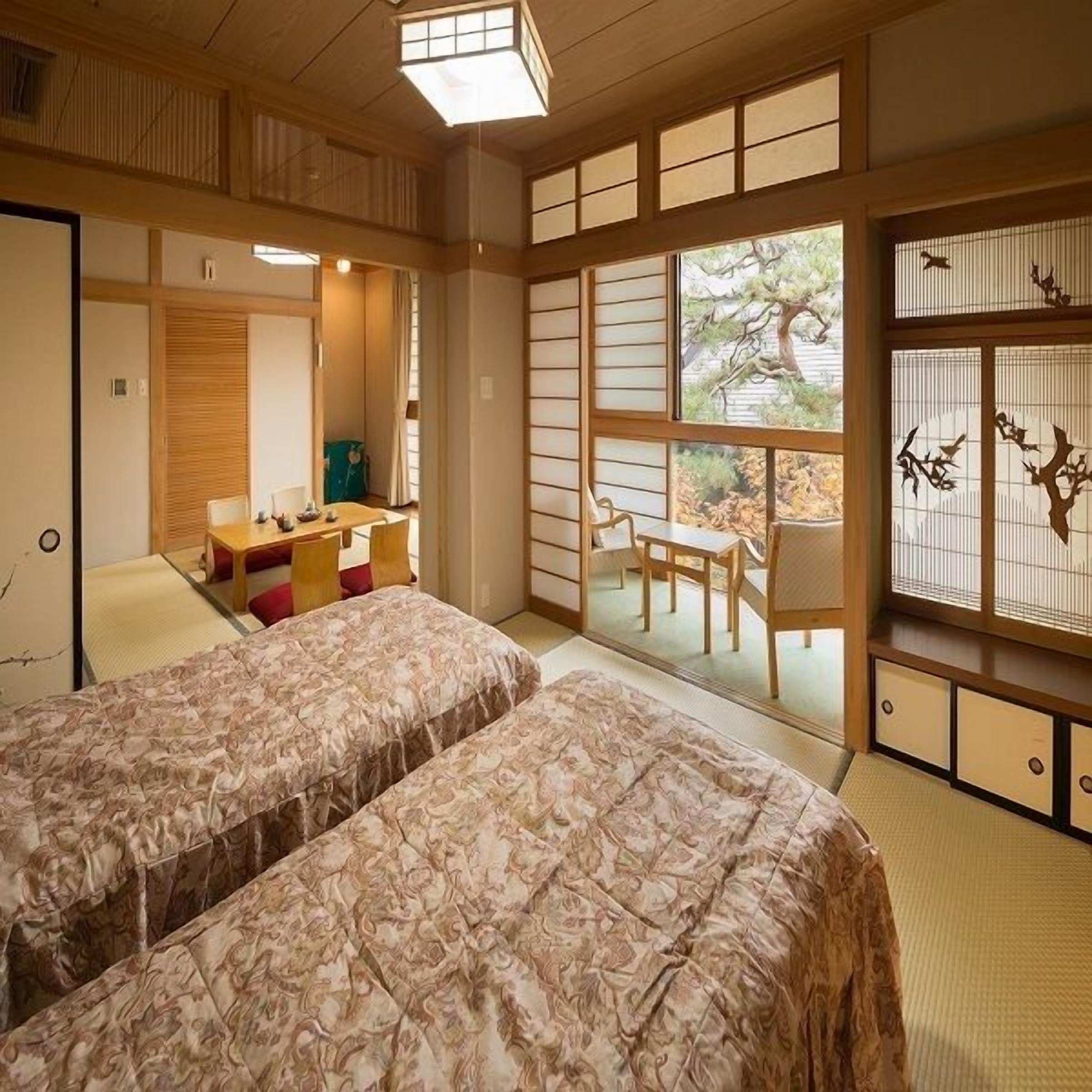 Um quarto em estilo tradicional japonês com piso de tatame, futon, uma pequena escrivaninha e uma porta deslizante que dá para uma área externa.