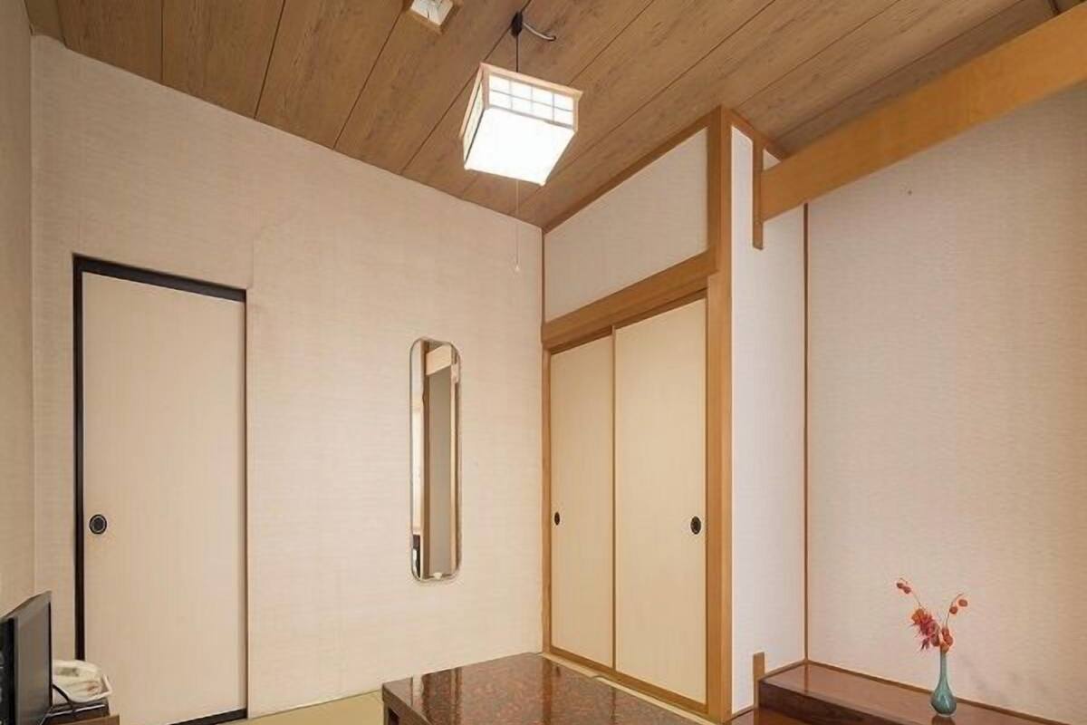 Ein traditioneller japanischer Raum mit Tatami-Boden, einem niedrigen Holztisch, einem Spiegel und einer Schiebetür.