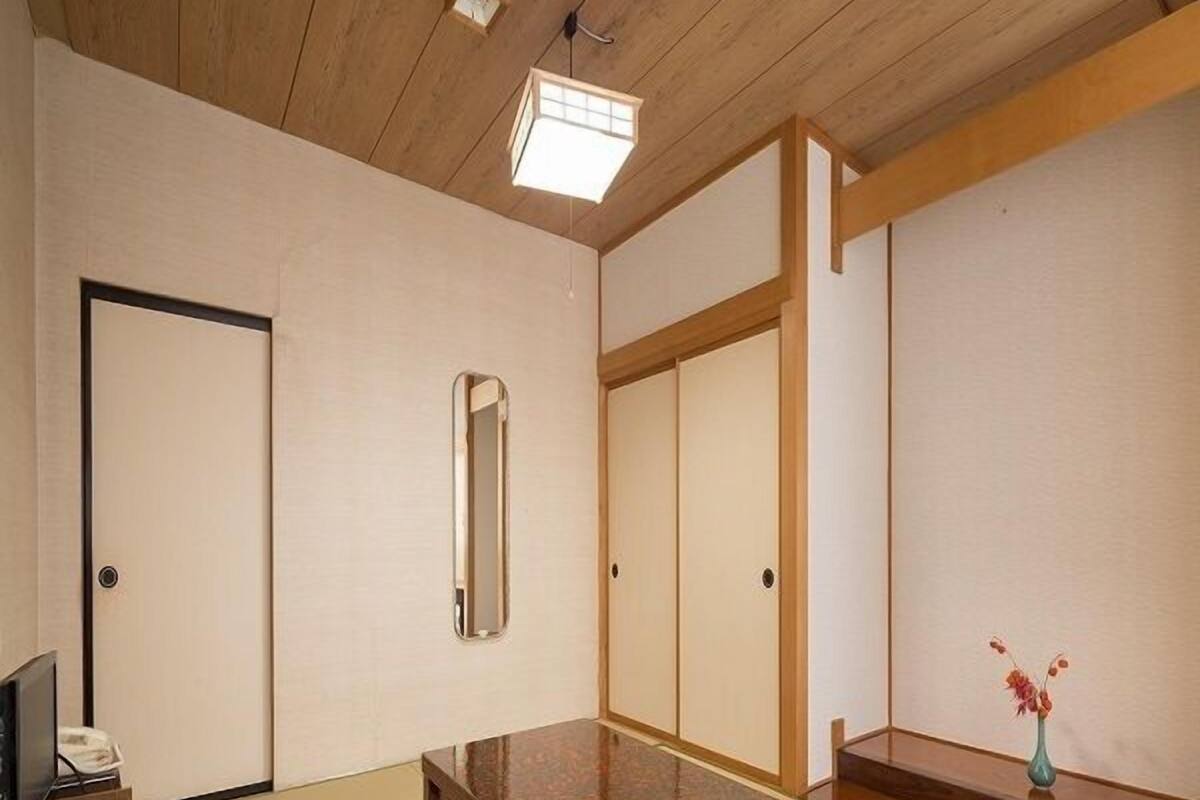 Ein traditioneller japanischer Raum mit Tatami-Boden, einem niedrigen Holztisch, einem Spiegel und Schiebetüren.