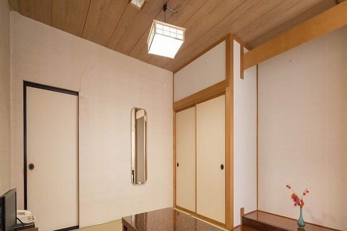 Um quarto japonês tradicional com tatames, uma mesa de madeira baixa, um espelho e portas deslizantes.