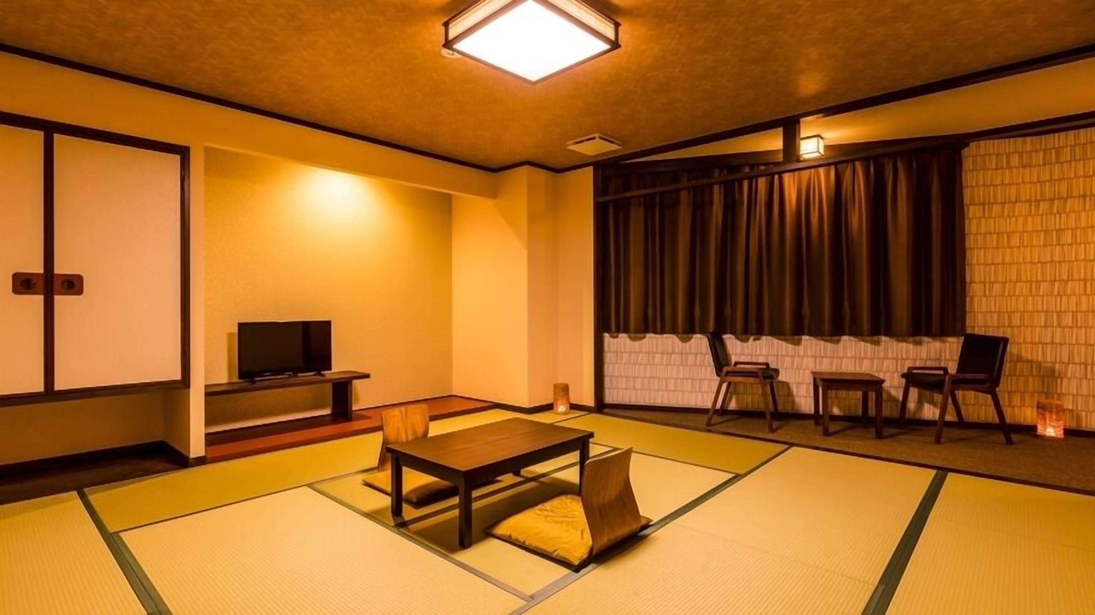 A traditional Japanese room with tatami flooring, a low table with cushions, a television, and sliding doors.