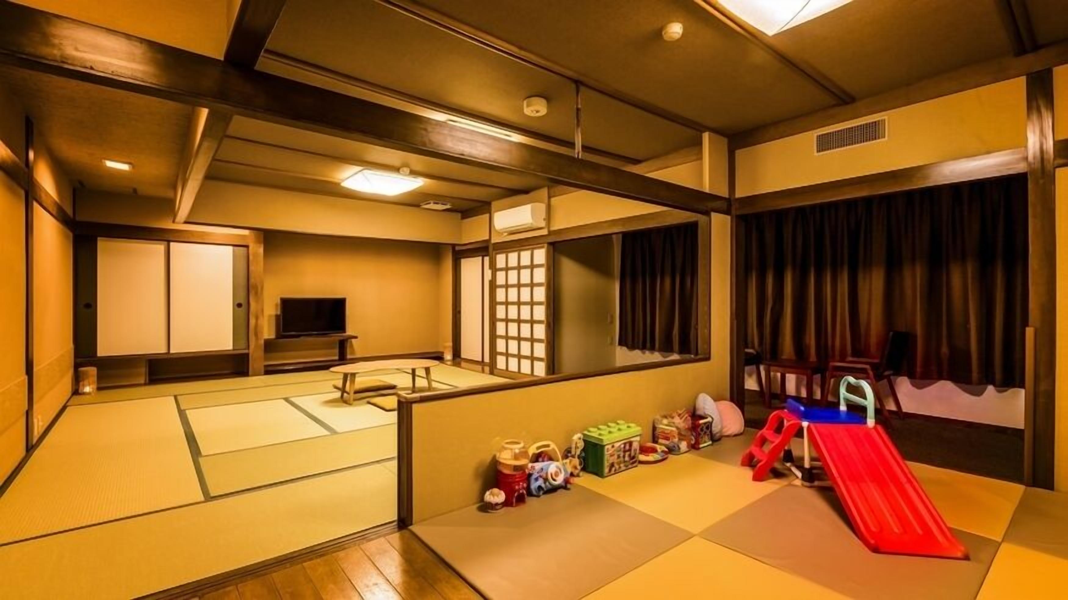 A traditional Japanese-style room with tatami flooring, a television, sliding doors, and a small play area with toys and a slide.