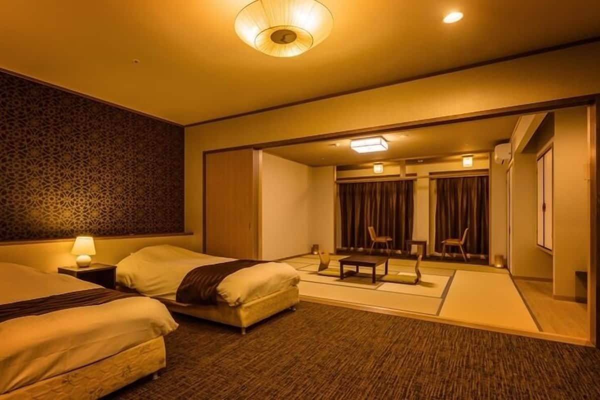 A hotel room with two beds, a sitting area with chairs, a small table, and a decorative wall.