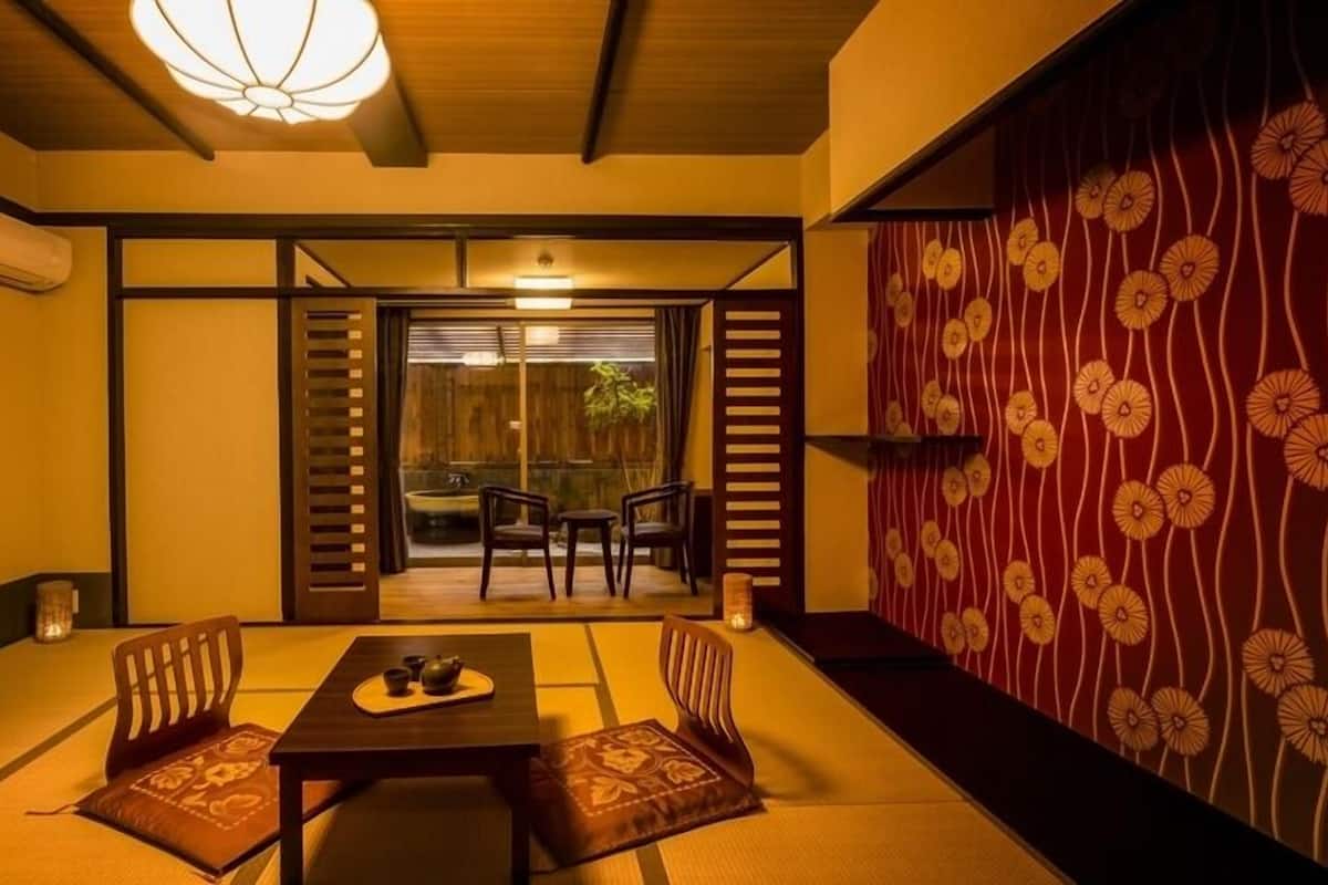 A traditional Japanese room with tatami flooring, a low table with a tea set, and sliding doors leading to an outdoor area.